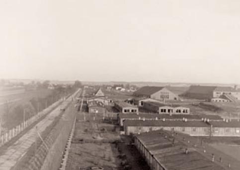 Black and white photo with an aerial view: barracks and building complexes behind a spiked fence