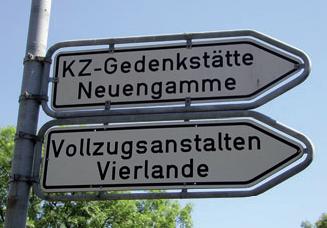 A photo of two signposts, one on top of the other. The upper one says: "Neuengamme Concentration Camp Memorial", the lower one says "Vierlande Correctional Facilities".